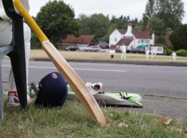 A player waiting to bat relaxes during a village cricket match between Tilford and Grayswood being played at Tilford Green in Waverley, Surrey.