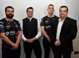 Two players sporting the away jersey with representatives from Pro Carrier.