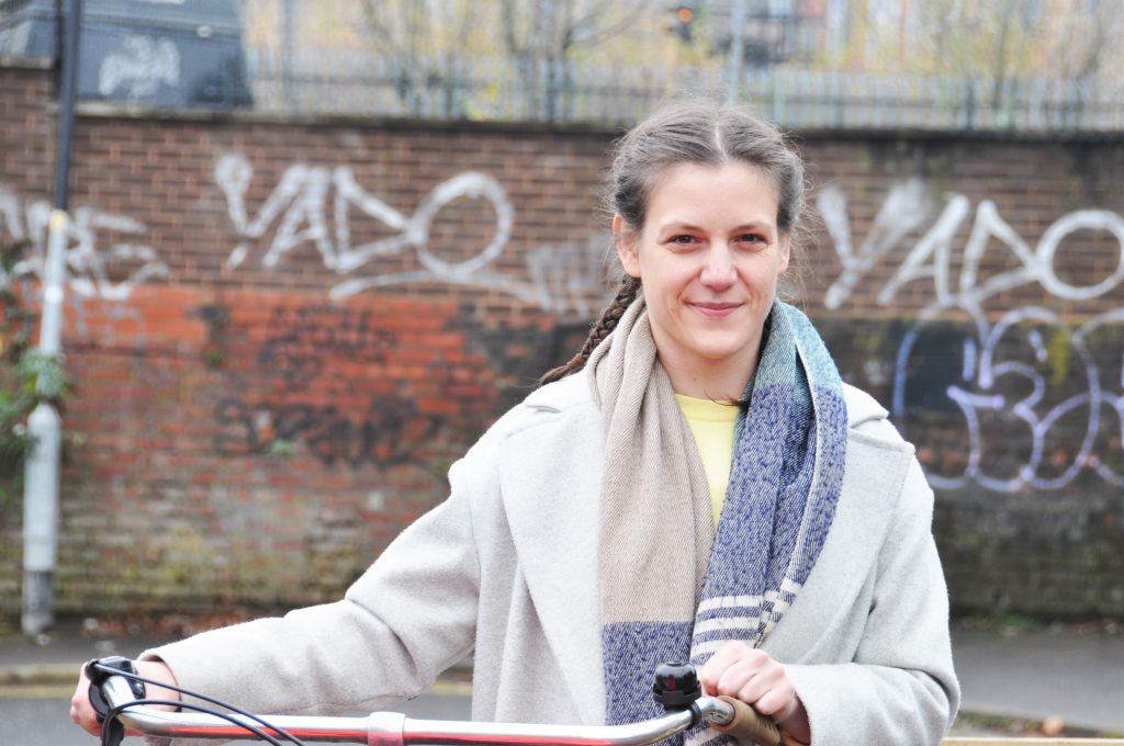 Harrie Larrington-Spencer standing with her bike. She is a PhD researcher at the University of Salford.