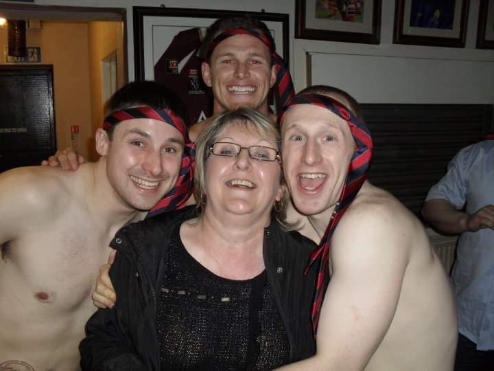 Alfrieda Kindon with three shirtless rugby players