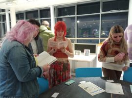 People reading the zines provided in the exhibition. Credit: Mel Cionco