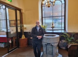 Rector Andy Salmon stands in front of the font where Webb-Ellis