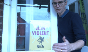 Doctor David McKelvey standing with an Extinction Rebellion poster, the group he was with on Lambeth Bridge. image credit: sam Taylor