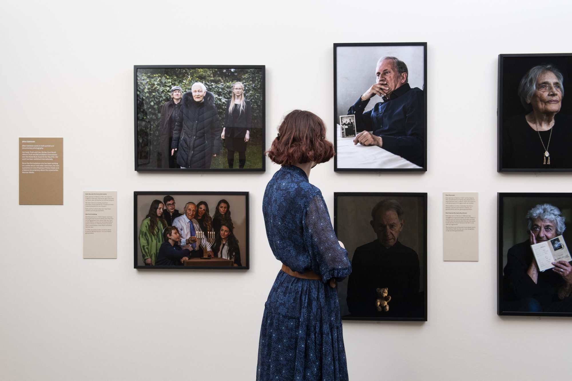 © IWM (1048) A visitor looks at portraits taken by Jillian Edelstein. Installation shot of Generations: Portraits of Holocaust Survivors at IWM London (6 August 2021 – 9 January 2022).