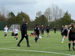 Young girls playing football on pitch 